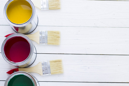 房屋翻新概念彩色油漆罐和漆刷在木制背景顶部视图