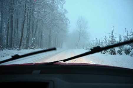 冬天开车。 从一辆汽车的内部观看雪道上的司机的眼睛。 冬季驾驶安全的概念。