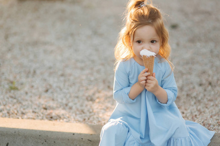 穿着蓝色连衣裙的漂亮小女孩吃冰淇淋