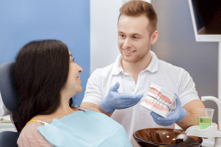 牙齿护理。 英俊的年轻专业牙医，向他的资深病人解释如何在牙科诊所工作的牙齿后护理牙齿霉菌专业沟通医疗服务理念