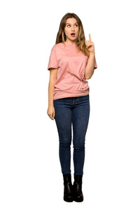 一个穿着粉色毛衣的青少年女孩在孤立的白色背景上挠头时思考一个想法