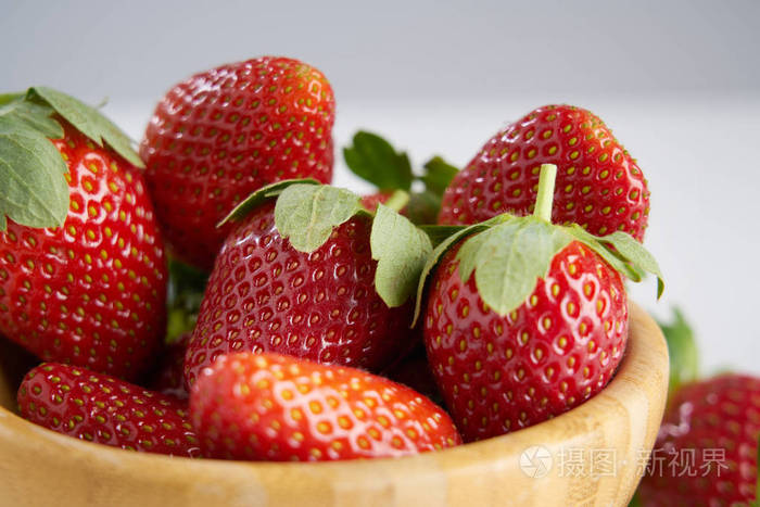 把新鲜的,完美的浆果,红色的草莓放在木制的盘子里,以健康的饮食和