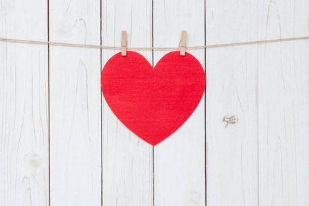 红色的心挂在白色的木头背景和复制空间。
