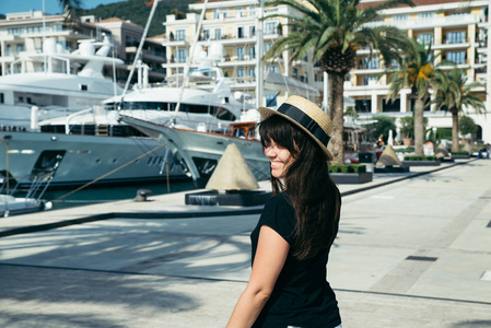 微笑的女人肖像在码头与游艇的背景。 夏季时间概念
