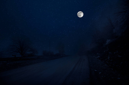 满月之夜，山路穿过森林。 夜晚风景优美的乡村道路，有大月亮