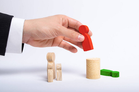 s hand of a businessman in a business suit holds a wooden figure