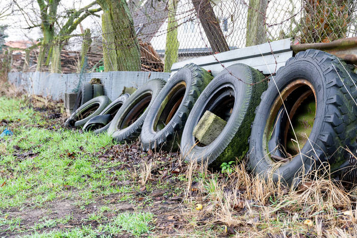 不同大小的旧轮胎靠在篱笆上
