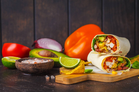 烤玉米卷与鸡豆，玉米，西红柿和鳄梨在木板黑暗的背景。 墨西哥肉玉米煎饼食物。