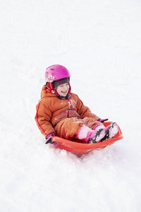 一个孩子骑着雪橇从山上下来。