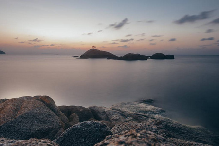 海上岩石海岸的日落。 太阳正在离开地平线。 夕阳下的石头和大海