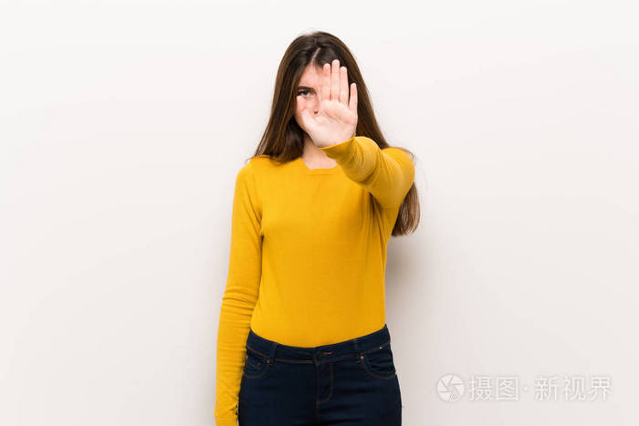 年轻女子穿着黄色毛衣做着停止的手势否认自己有错误的想法