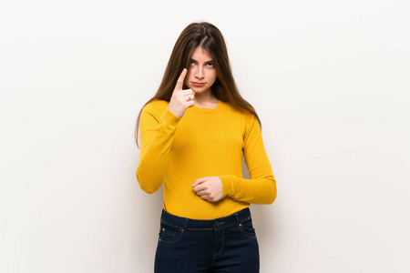 年轻女子穿着黄色毛衣，因糟糕的情况而沮丧，指着前面