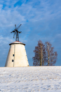 阳光明媚的冬日，空旷的乡村景观，积雪覆盖地面，背景是有趣和快乐的大废弃风车