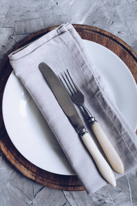 叉刀灰色亚麻餐巾纸和白板在木板上的混凝土背景。 食物背景。 漂亮的安排。 菜单模型。 平躺着。 上面的风景。