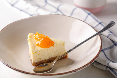 白色背景的盘子里放着橙色果酱的芝士蛋糕