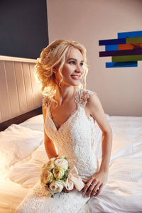 早上好的新娘。 一个穿着白色婚纱的女人手里拿着一束花。 美丽的金发女郎准备结婚典礼