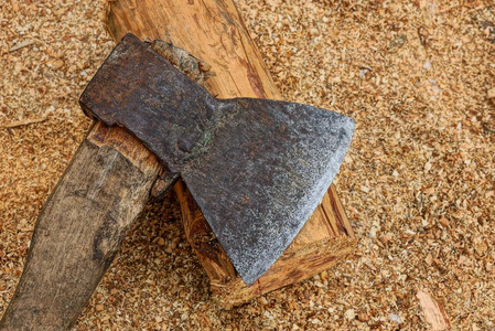 一把旧钢斧斧子和一根棕色的木头在外面的小木屑上