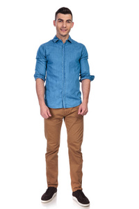 年轻英俊的男人穿着蓝色衬衫，站在白色的背景上，卷起袖子，全身的照片