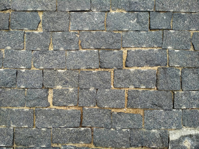 石砖。 有质感的砖墙紧贴着砖灰色的瓷砖。 街石纹理背景。