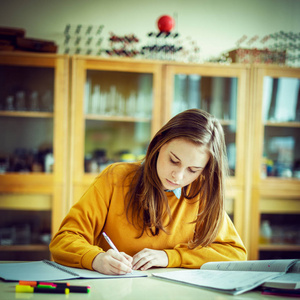 年轻女大学生在化学课上写笔记。 课堂上专注的学生。 真实的教育理念。