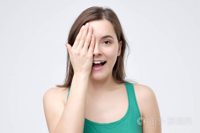 微笑的女人用手捂住眼睛站在灰色带复印空间的相机前买眼镜前视力检查