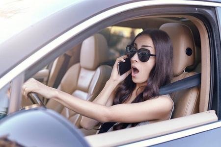 开车时在智能手机上说话的震惊女人的肖像