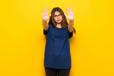 一位戴着眼镜的年轻女子在黄色的墙上做手势，表示对观点的失望