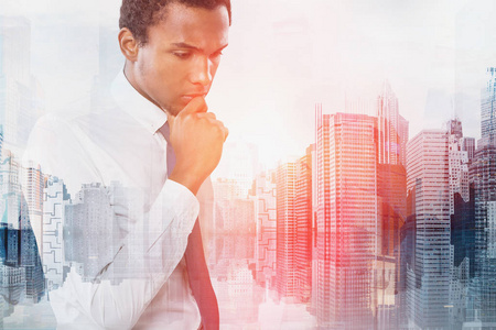 忧郁的非裔美国商人的肖像，穿着衬衫和领带，站在城市景观的背景下思考。 决策的概念。 色调图像双曝光