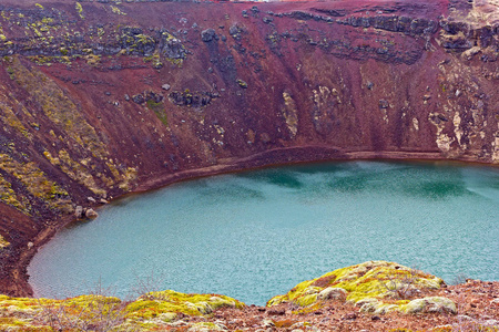 冰岛南部一个火山口湖的一个边缘有独特的红色岩石和植被。 冰岛欧洲容易识别的火山口湖之美。