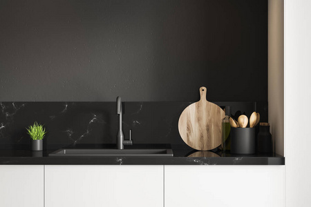 黑色大理石厨房水槽站在白色台面上，房间里有黑色的墙壁。 木制圆形切割板和小盆栽。 3D渲染