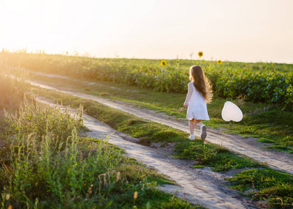 小女孩在草地上的田野里戴着白色的心。 快乐情人节和母亲节的概念。 软焦