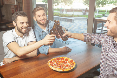 男人一起喝啤酒，在咖啡馆里吃披萨