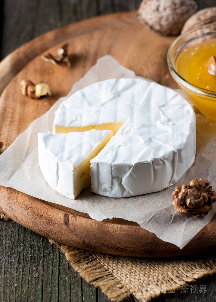 布里型奶酪卡蒙伯特奶酪新鲜的布里奶酪和一片木板上的坚果蜂蜜和树叶