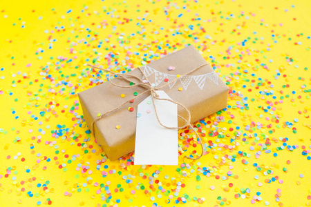 带黄麻绳的彩色礼品盒。 黄色背景。 派对或生日礼物。