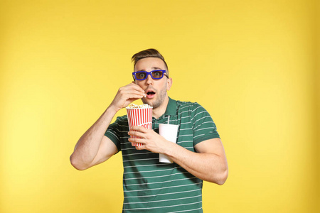 在彩色背景电影放映期间带3D眼镜爆米花和饮料的情绪化男人