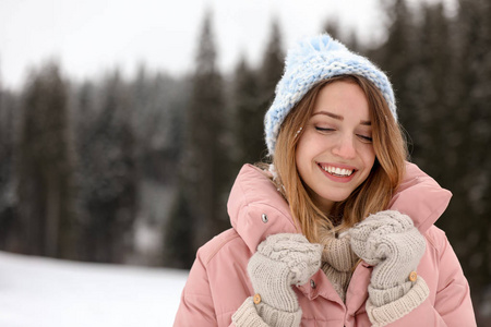 年轻女子穿着温暖的衣服在户外空间发短信。 寒假