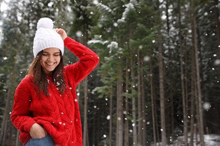 年轻的女人穿着温暖的毛衣在户外下雪的日子里发短信。 寒假