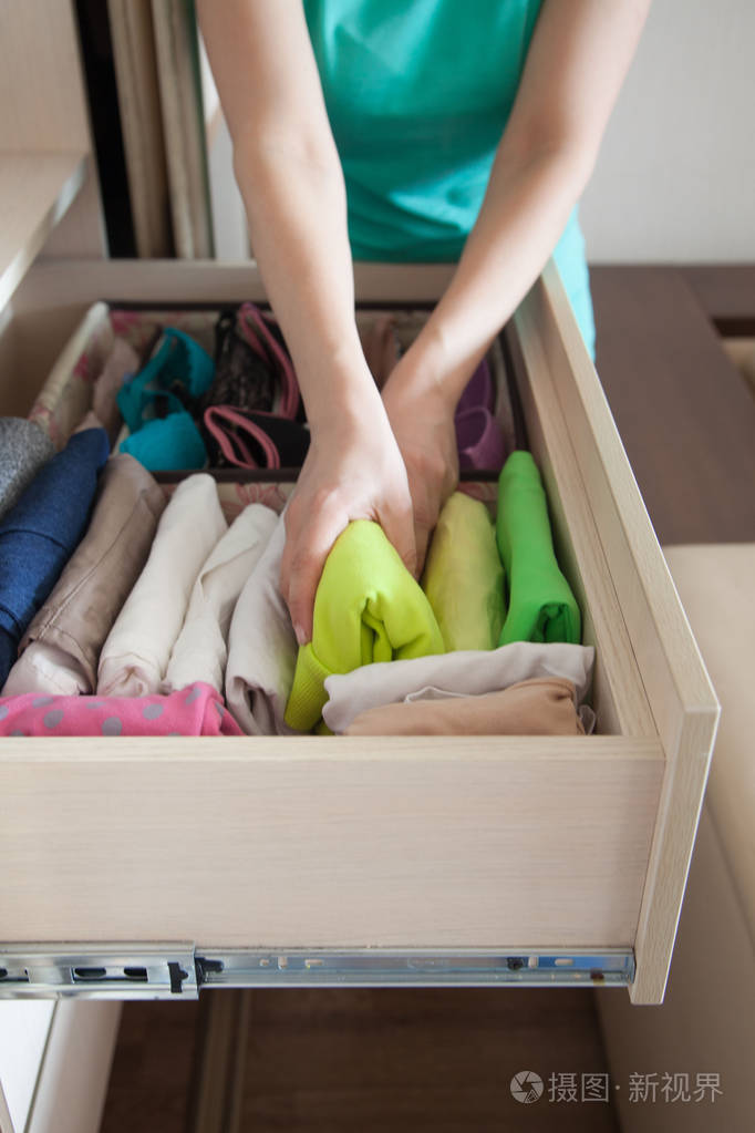 那女人把t恤衫叠在抽屉里一个女人正在整理壁橱垂直存放衣物