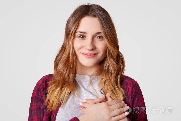 美丽的女人保持双手在胸前有迷人的微笑,表达良好的态度和感情,穿着