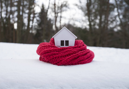 冬季住宅供暖系统的概念和寒冷的雪天，带针织帽的房子模型