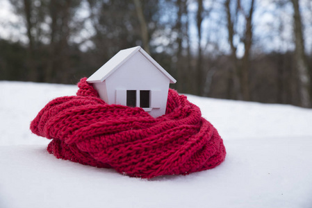 冬季住宅供暖系统的概念和寒冷的雪天，带针织帽的房子模型