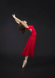 一个穿红色舞蹈芭蕾长发的女孩。 黑暗背景下的摄影棚。