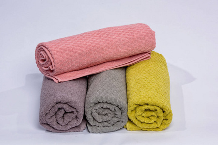 家庭装饰。 彩色毛巾折叠成卷。 织物的质地。 白色背景上的明亮毛巾。 特里毛巾。 织物类型