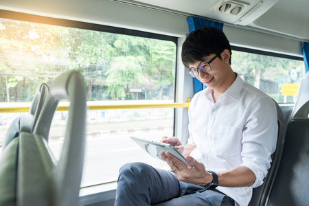 英俊的时髦现代男人使用数字触摸屏平板电脑工作和连接到网络在电车或公共汽车上旅行。