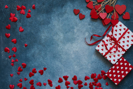情人节背景。蓝色背景上的红心和礼品盒。复制空间，俯视图..情人节的平躺庆祝理念