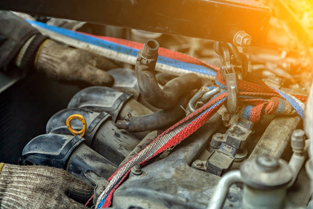 在汽车修理车间使用气动手动起重机在旧车上安装电机。汽车机械拆卸发动机的工作