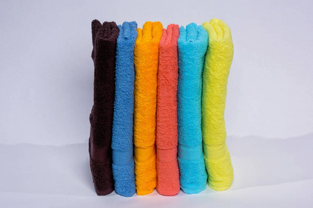 家庭装饰。 彩色毛巾叠在一起。 织物的质地。 白色背景上的明亮毛巾。 特里毛巾。 织物的类型。