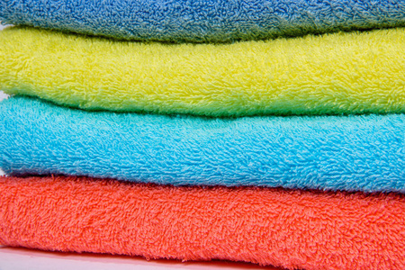 家庭装饰。 彩色毛巾叠在一起。 织物的质地。 白色背景上的明亮毛巾。 特里毛巾。 织物的类型。