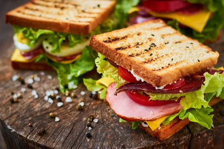 自制三明治与火腿, 生菜, 奶酪和西红柿在木制背景