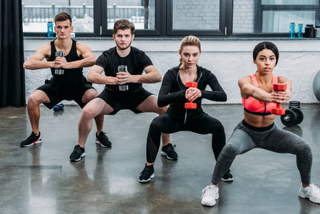 在医院两个运动的女人在蹲着的时候用壶铃练习运动的年轻男女在健身